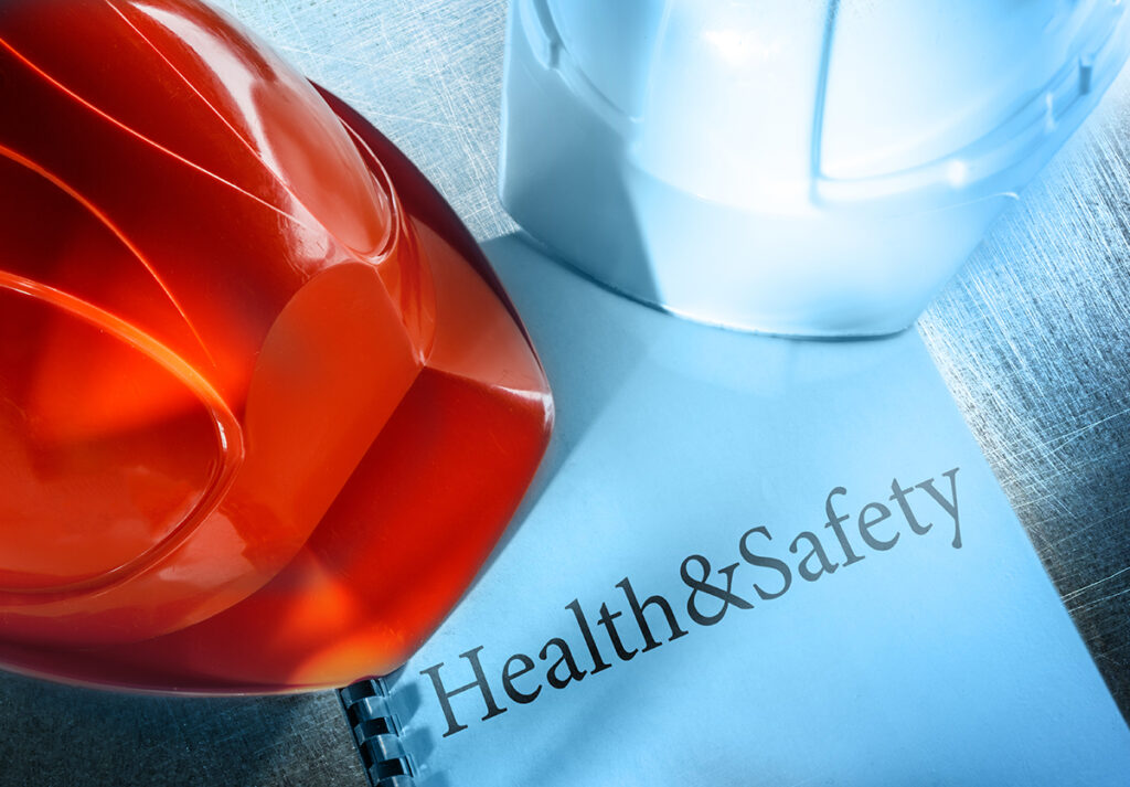 Picture showing two hard hats on a Health and Safety policy document