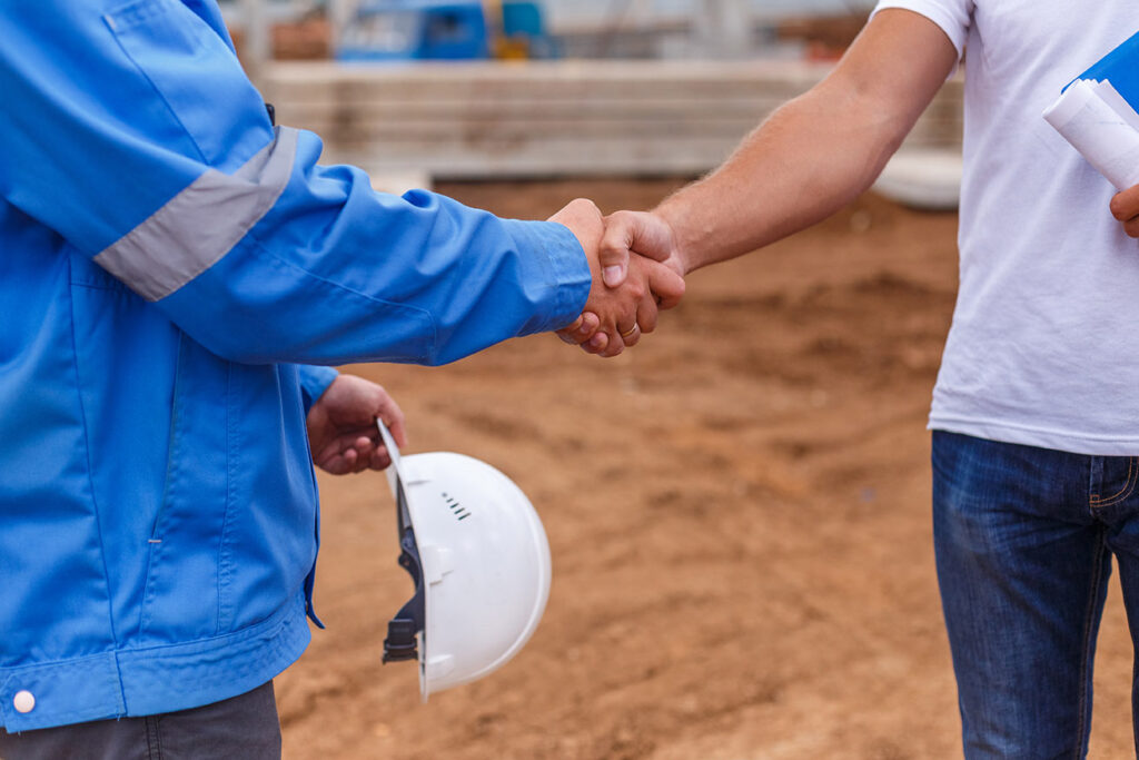 Architect and Construction worker shaking hands on building site