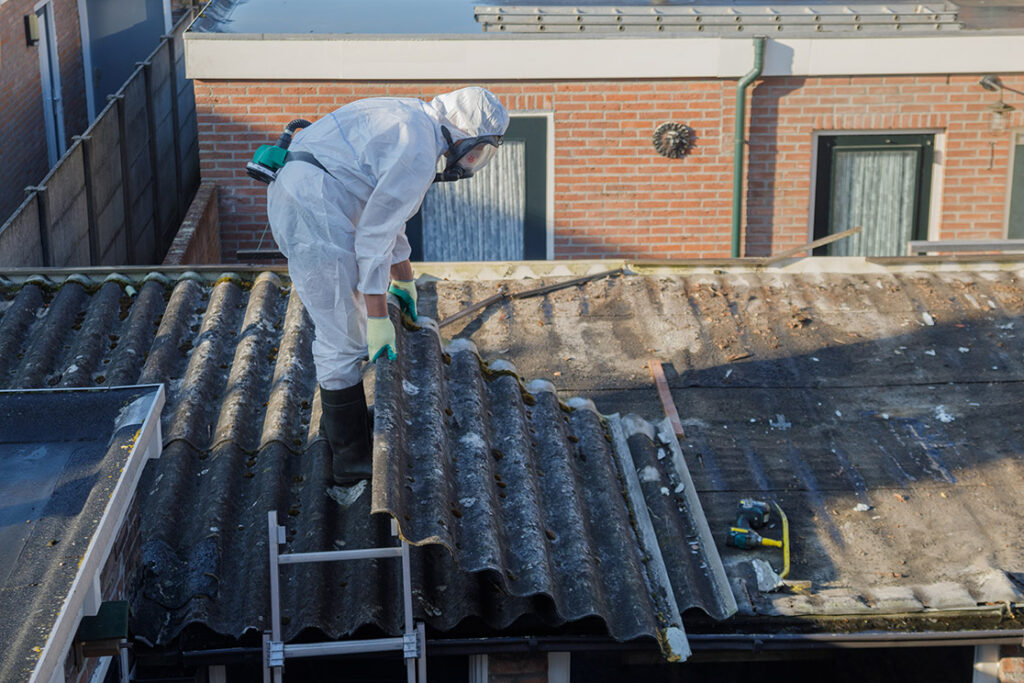 Professional asbestos removal. Men in protective suits are removing asbestos cement corrugated roofing